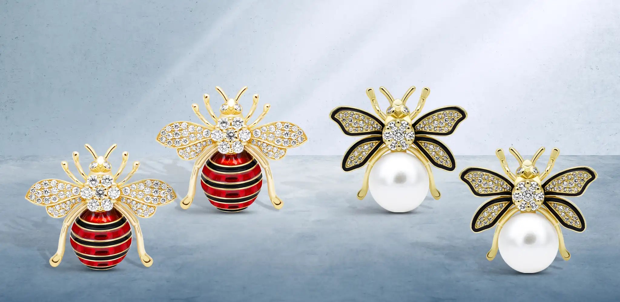 Two pairs of gold bee-shaped earrings with diamond-studded wings, displayed on a soft blue background | Singhvi Jewels Signature Bees Collection