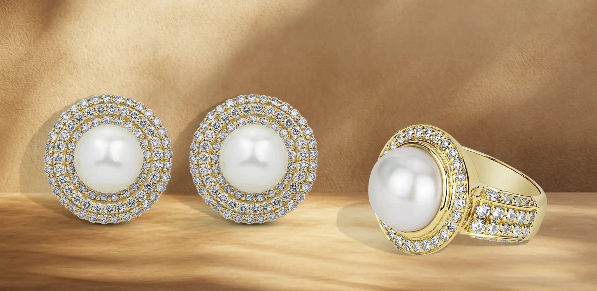 A pair of pearl and diamond earrings beside a matching pearl ring with diamond accents on a warm neutral background | Singhvi Jewels Cocktail Jewelry Collection