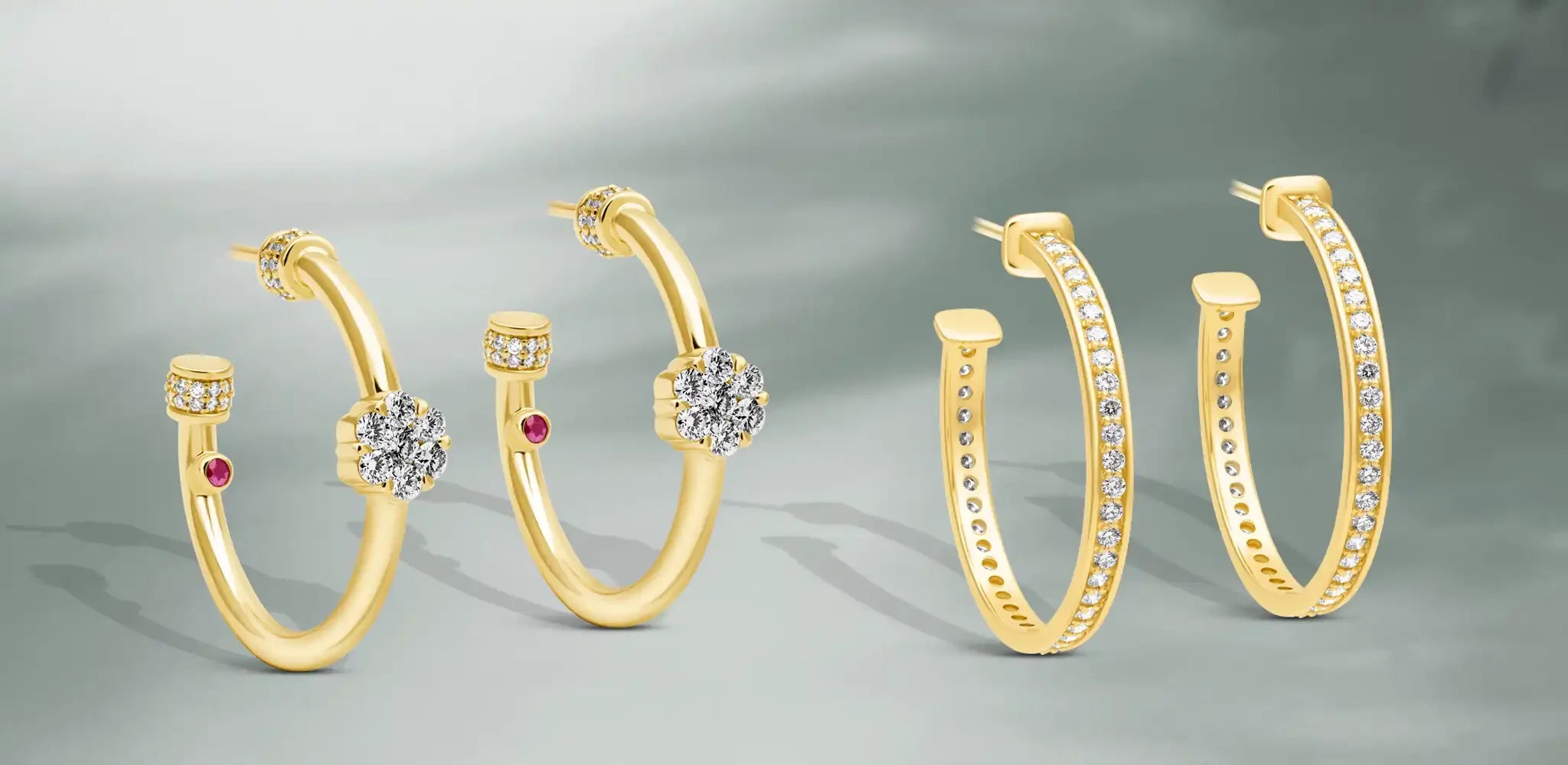 A collection of gold hoop earrings featuring diamond accents, floral diamond motifs, and subtle ruby gemstone on a soft gray background | Singhvi Jewels Hoop Earrings Collection