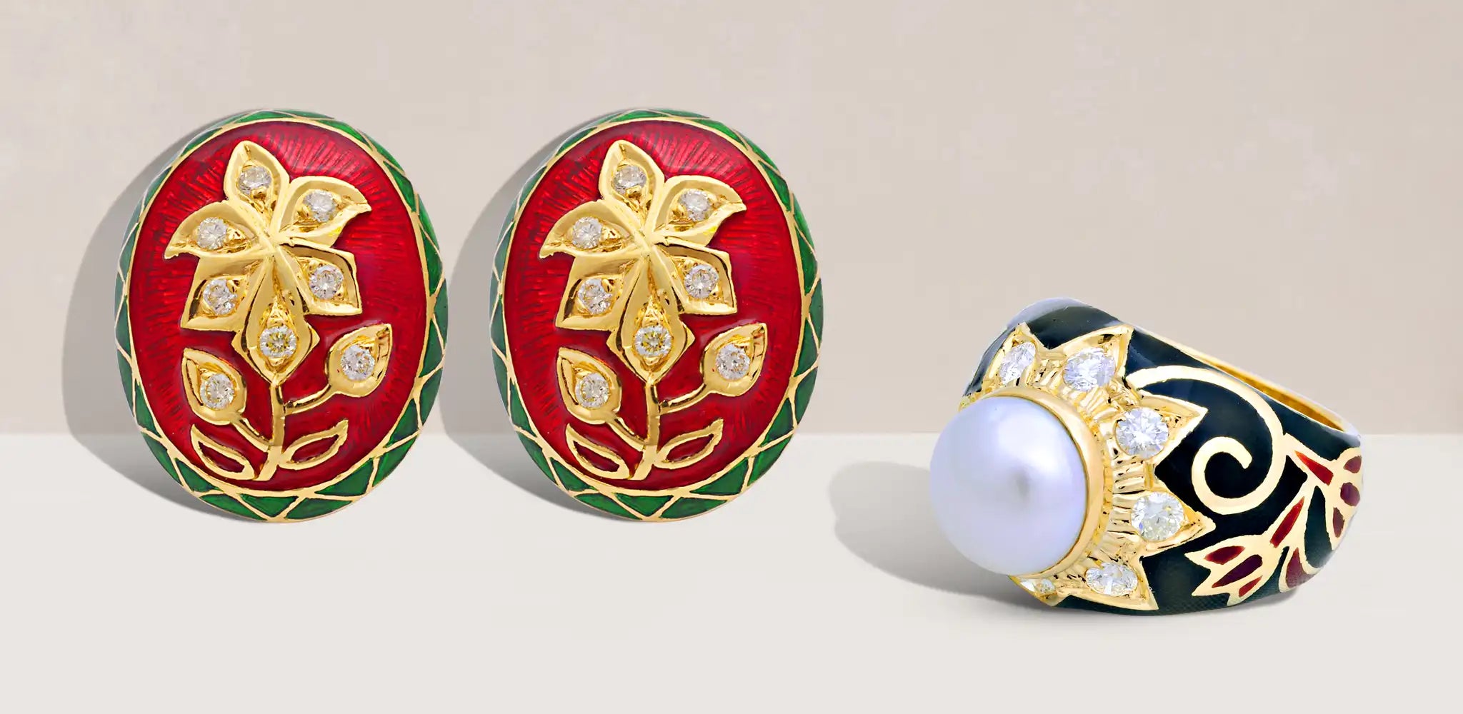 A pair of oval earrings with red and green enamel details and gold floral designs with a white pearl center, diamond accents, and black enamel patterns | Singhvi Jewels Indian Jewelry Collection